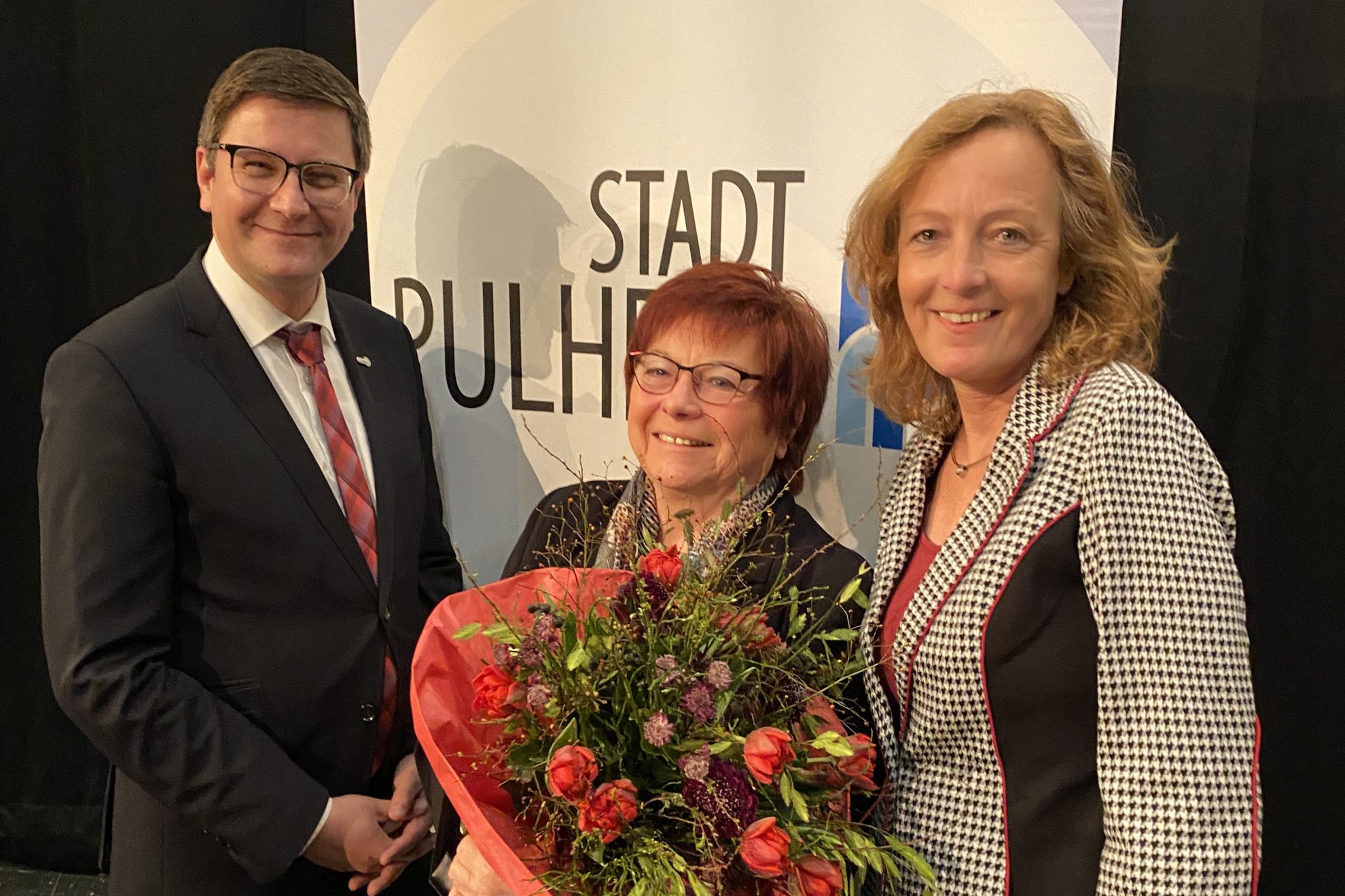 Torsten Rekewitz und Sylvia Fröhling gratulieren Marlies Stroschein mit einem Blumenstrauß